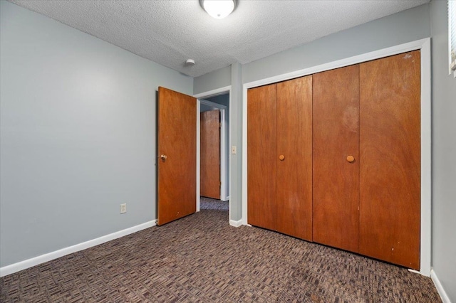 unfurnished bedroom featuring a closet, a textured ceiling, and dark colored carpet