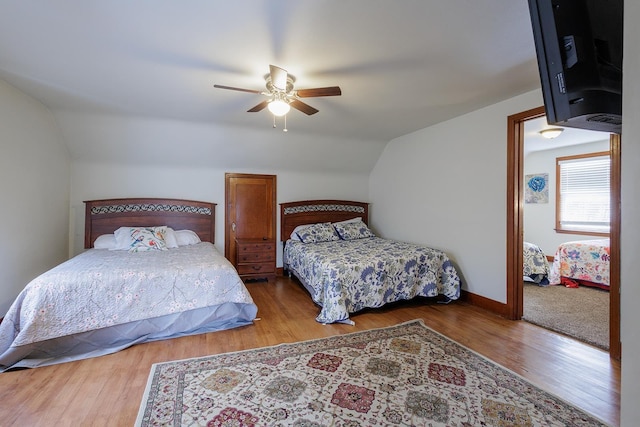 bedroom featuring baseboards, lofted ceiling, wood finished floors, and a ceiling fan