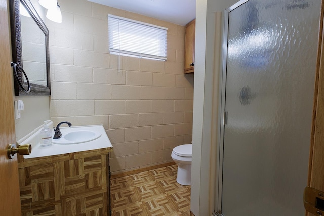 bathroom featuring a shower stall, concrete block wall, and toilet