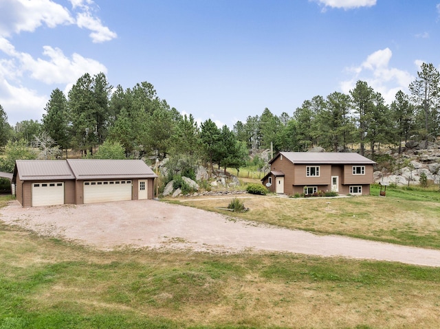 view of front of home with a garage, driveway, metal roof, and a front yard