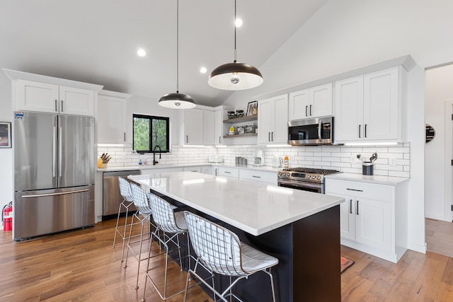 kitchen with backsplash, a center island, appliances with stainless steel finishes, wood-type flooring, and hanging light fixtures