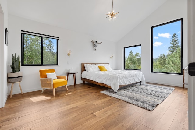 bedroom with light wood-type flooring, high vaulted ceiling, and a chandelier