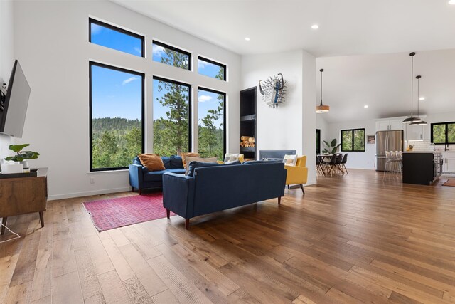 living room with a towering ceiling, light wood-type flooring, and plenty of natural light