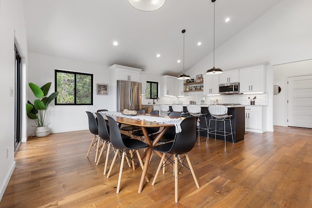 dining space featuring light hardwood / wood-style floors and high vaulted ceiling