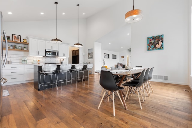 dining space with hardwood / wood-style floors and high vaulted ceiling