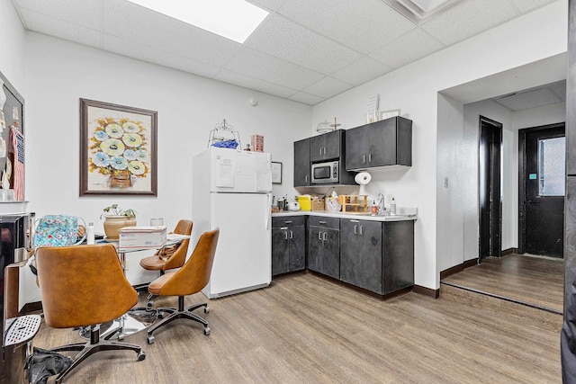 kitchen featuring sink, a paneled ceiling, stainless steel microwave, light wood-type flooring, and white fridge