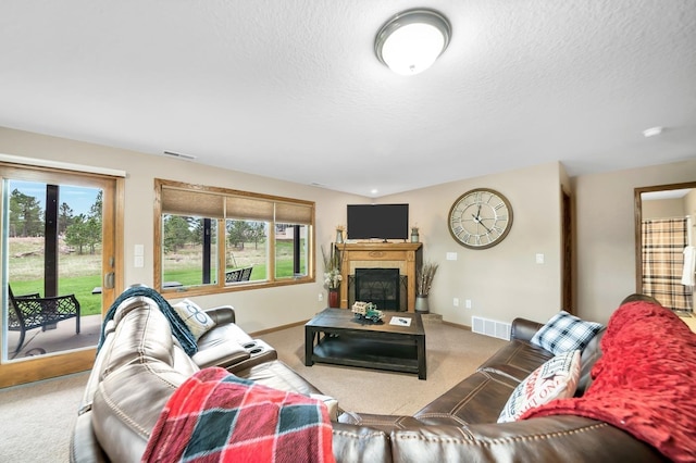 carpeted living room with visible vents, a fireplace, and a textured ceiling