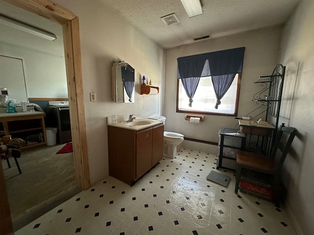 bathroom with tile patterned floors, toilet, a textured ceiling, and vanity