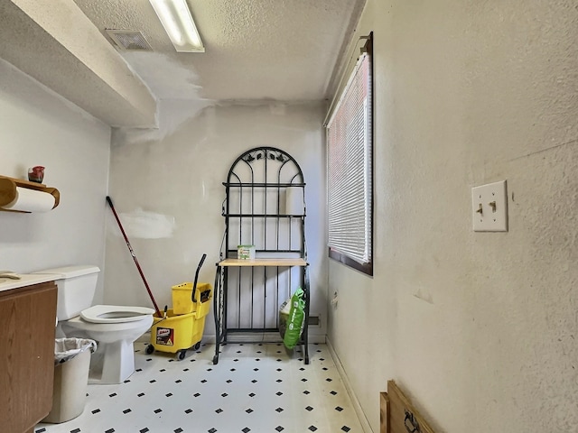 bathroom with toilet, a textured ceiling, tile patterned flooring, and vanity