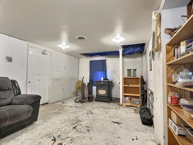 living room featuring visible vents, a wood stove, and unfinished concrete floors