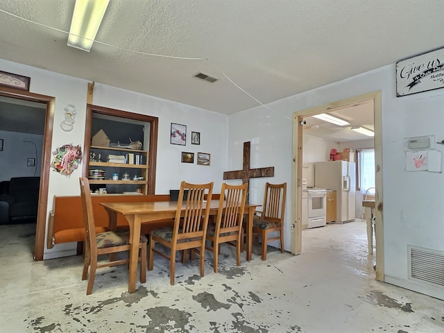 dining area with unfinished concrete floors, a textured ceiling, and visible vents