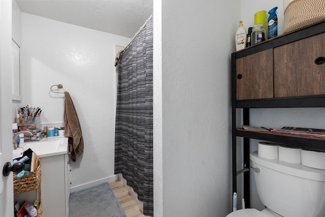 bathroom with toilet, hardwood / wood-style flooring, walk in shower, and vanity