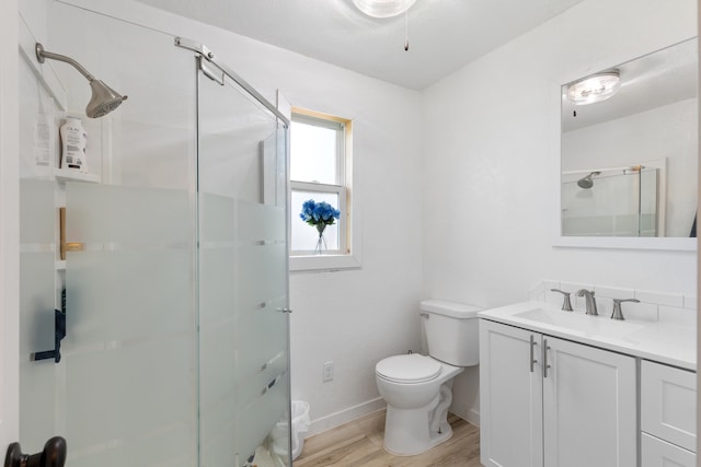 bathroom featuring a shower with shower door, vanity, hardwood / wood-style floors, and toilet