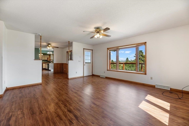 unfurnished living room featuring ceiling fan, dark wood-type flooring, and a textured ceiling