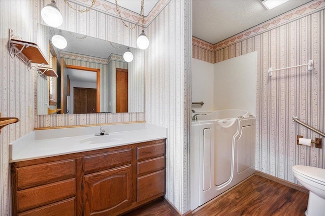 bathroom featuring toilet, a tub, vanity, and wood-type flooring