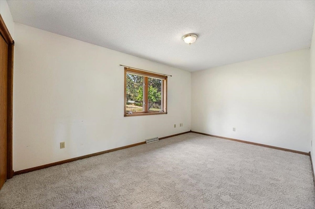 unfurnished room with carpet and a textured ceiling