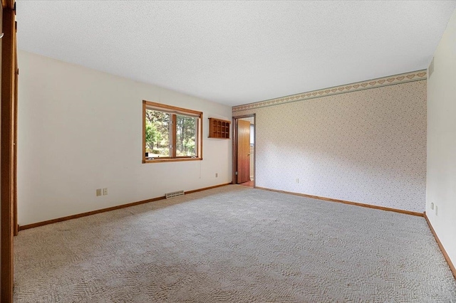 carpeted empty room with a textured ceiling