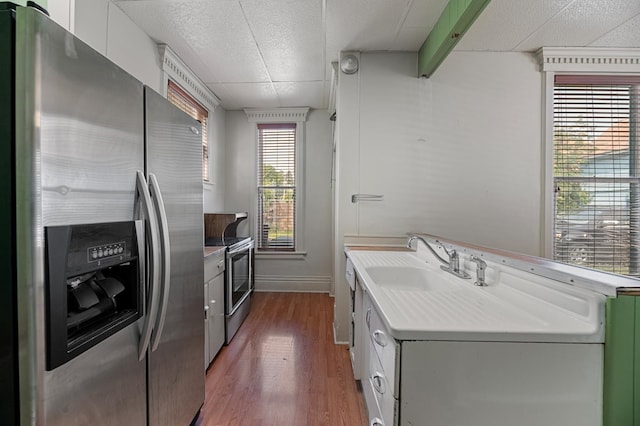 kitchen with a healthy amount of sunlight, stainless steel appliances, white cabinets, and dark wood-type flooring