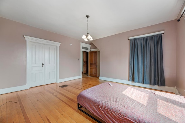 bedroom with light wood-type flooring and an inviting chandelier