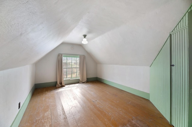 additional living space with a textured ceiling, hardwood / wood-style floors, and lofted ceiling