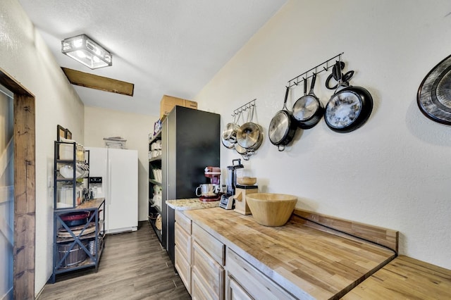 kitchen with white fridge with ice dispenser, dark wood-style flooring, butcher block countertops, and a textured ceiling