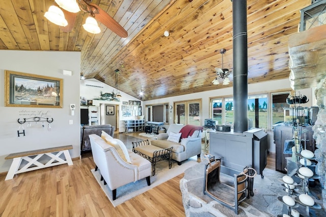 living area featuring ceiling fan, wood ceiling, vaulted ceiling, light wood-type flooring, and a wood stove