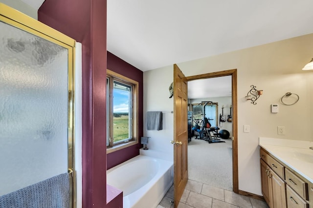 bathroom featuring tile patterned flooring, vanity, a bath, and baseboards