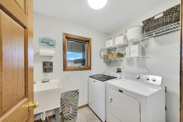 washroom with light tile patterned floors, a sink, separate washer and dryer, laundry area, and baseboards