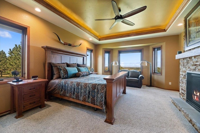 bedroom featuring multiple windows, ceiling fan, a fireplace, and light carpet