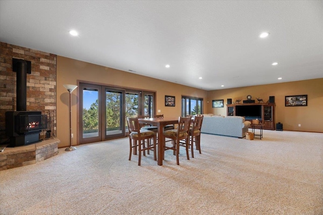 carpeted dining space with a wood stove and a textured ceiling