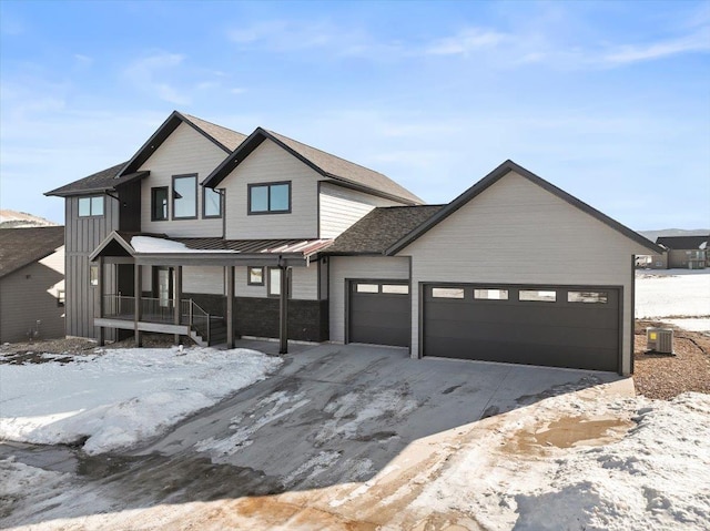 view of front of property with a porch, an attached garage, central air condition unit, board and batten siding, and a standing seam roof