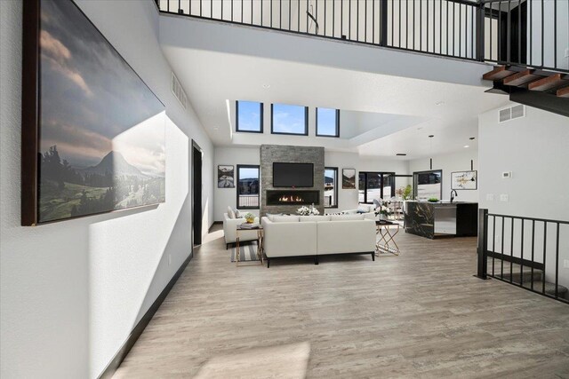 living room featuring hardwood / wood-style flooring, a towering ceiling, and a fireplace