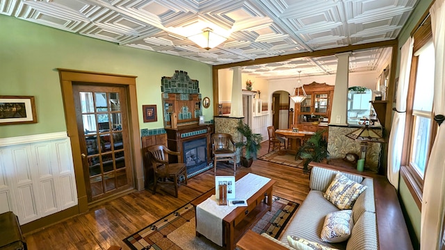 living room with crown molding, dark wood-type flooring, coffered ceiling, and ornate columns