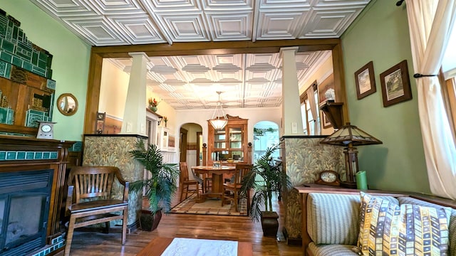 interior space featuring dark wood-type flooring, a fireplace, ornamental molding, and ornate columns