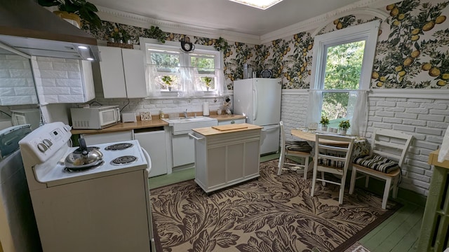 kitchen with white cabinetry, white appliances, plenty of natural light, and custom exhaust hood