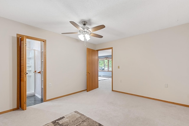 carpeted spare room with a baseboard heating unit, a ceiling fan, baseboards, and a textured ceiling