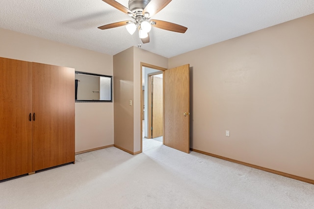 unfurnished bedroom featuring baseboards, light carpet, a textured ceiling, and ceiling fan