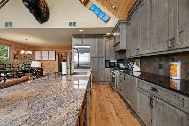 kitchen with stone countertops, hanging light fixtures, stainless steel gas range, and light hardwood / wood-style floors