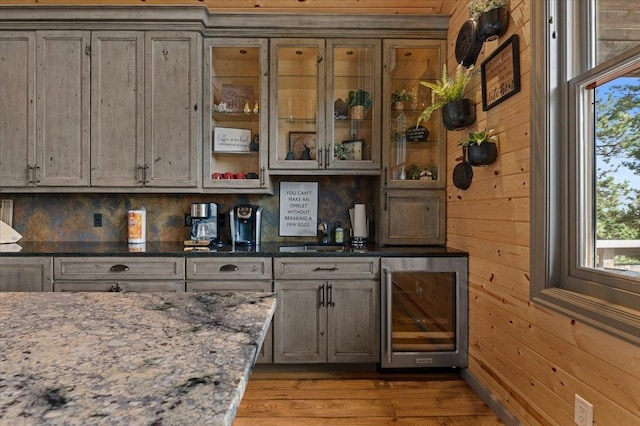 bar with stone countertops, a healthy amount of sunlight, hardwood / wood-style flooring, and wooden walls