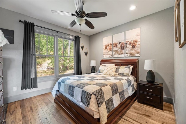 bedroom featuring light wood-type flooring, baseboards, and a ceiling fan