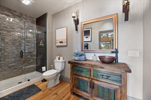 bedroom with ensuite bath, multiple windows, light hardwood / wood-style flooring, and ceiling fan