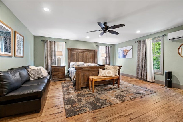 bedroom featuring baseboards, an AC wall unit, recessed lighting, and light wood-style floors