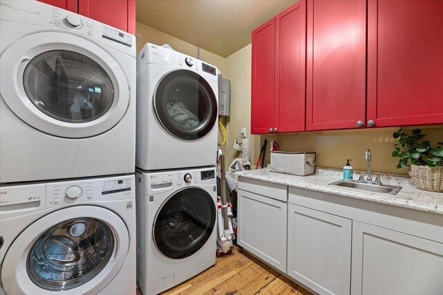 laundry area featuring light hardwood / wood-style flooring, stacked washing maching and dryer, cabinets, and sink