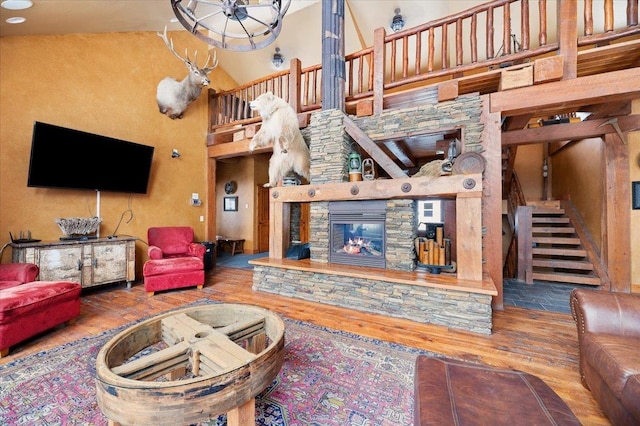 living room featuring high vaulted ceiling, wood-type flooring, and a stone fireplace