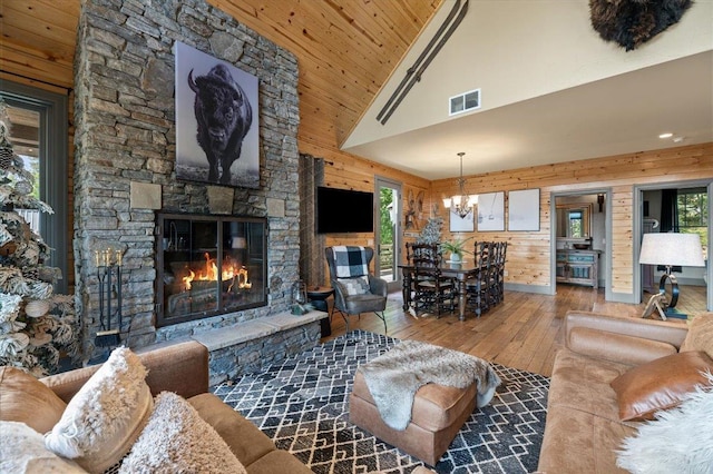 living room featuring a fireplace, wood-type flooring, visible vents, and wooden walls