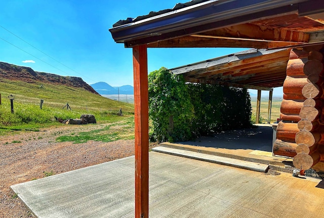 deck featuring a mountain view, a patio area, and a rural view