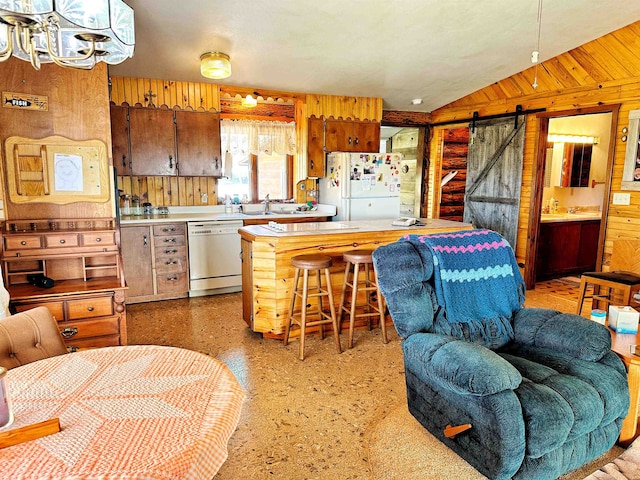 kitchen featuring wood walls, a barn door, stainless steel dishwasher, and white fridge