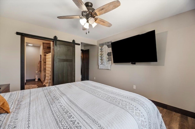 bedroom featuring a barn door, ceiling fan, and dark hardwood / wood-style floors