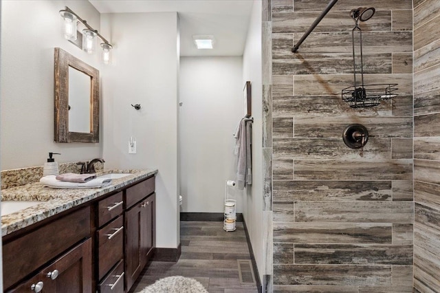 bathroom with hardwood / wood-style floors, a tile shower, and vanity