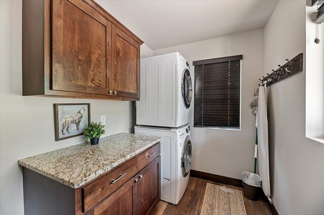 21185 Lost Camp Trl, Lead, SD 57754 - laundry room featuring stacked washer and clothes dryer, cabinet space, dark wood-style floors, and baseboards